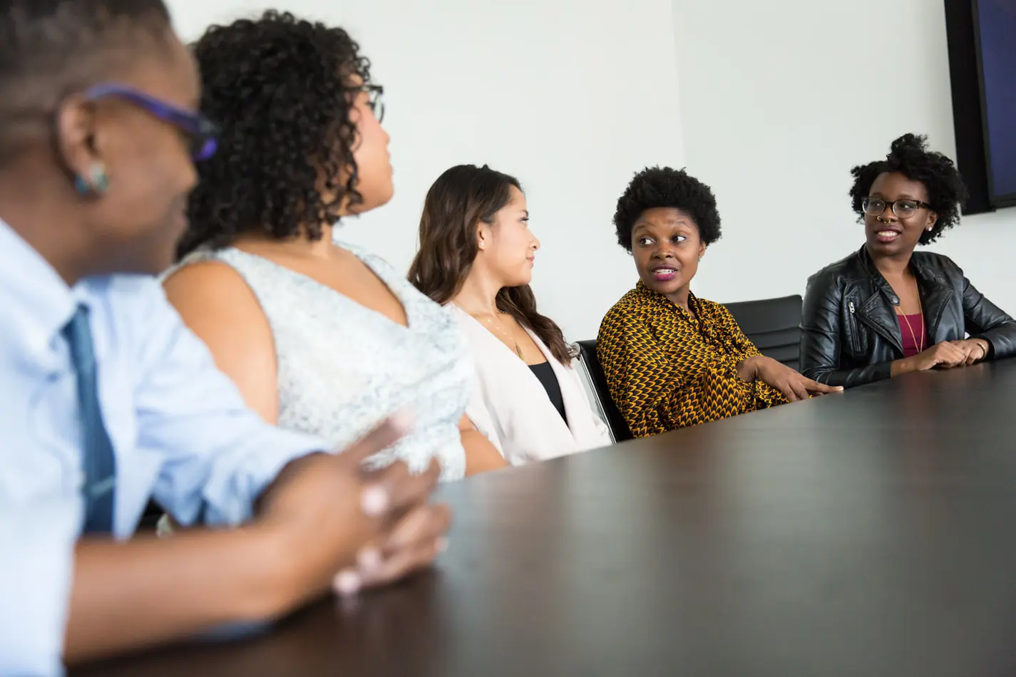 Five people sitting around a conference table during a meeting.