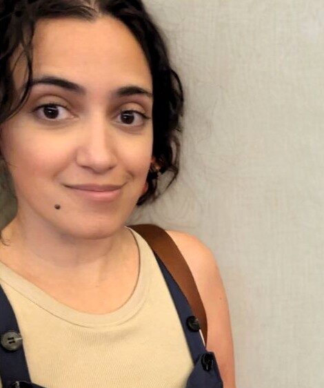Une femme qui a une tache de beauté sur la joue sourit à la caméra.
