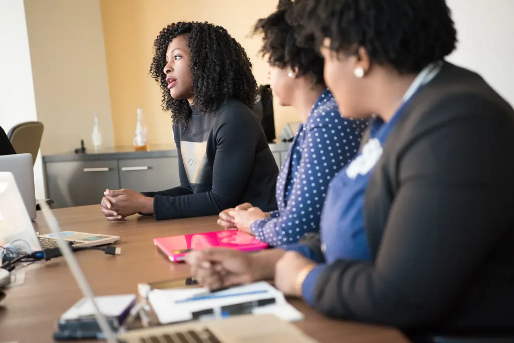 Three women sitting at a conference table during a meeting.